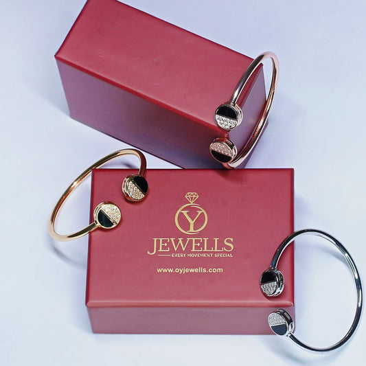 Gold bangles on a red 'Jewells' branded box with a light purple background